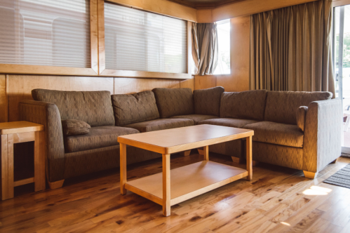 A cozy living room with a brown sectional sofa and a wooden coffee table on a polished wooden floor.