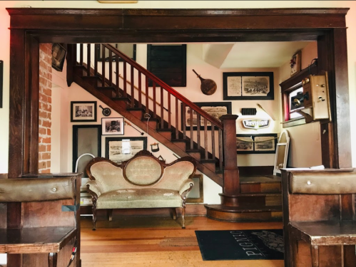 A cozy interior featuring a staircase, vintage photos on the walls, and an elegant sofa in a warm, inviting space.
