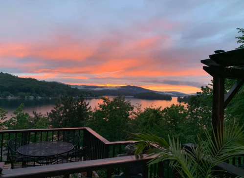 A serene lakeside view at sunset, with vibrant pink and orange skies reflecting on the water.
