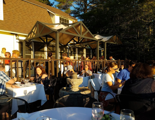 Outdoor dining scene with people at tables, a fountain, and a sunny atmosphere on a restaurant patio.