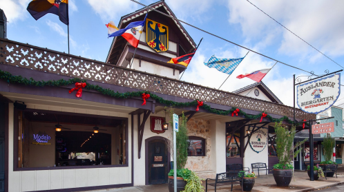 Exterior of a festive restaurant with flags, holiday decorations, and a sign reading "Auslander Biergarten."