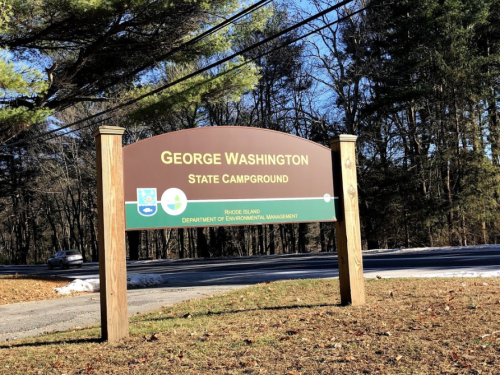 Sign for George Washington State Campground, surrounded by trees, with a clear blue sky above.