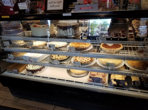 A display case filled with various cakes and pies, including cheesecakes, fruit pies, and chocolate desserts.