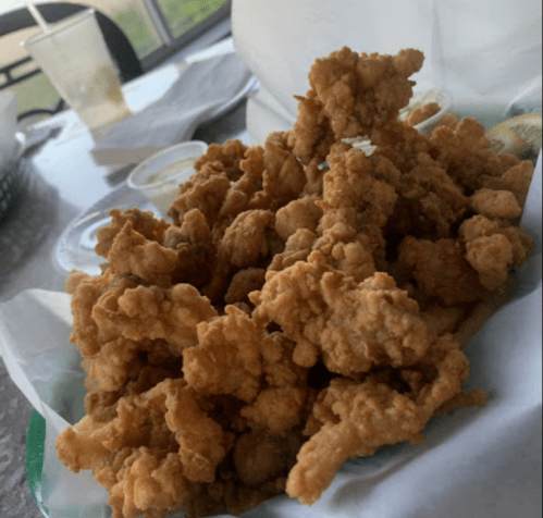 A close-up of a pile of crispy fried chicken pieces on a table, with dipping sauces in the background.