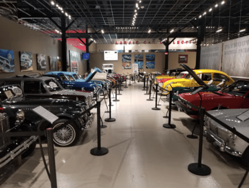 A collection of vintage cars displayed in a museum, with informational plaques and a well-lit interior.