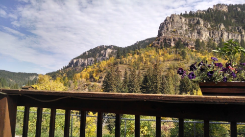 Scenic view of mountains with autumn foliage and a wooden railing in the foreground.