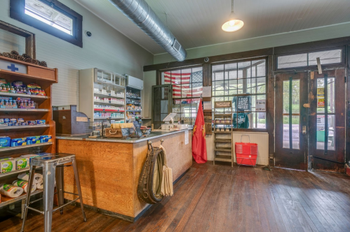 Interior of a vintage store with wooden counters, shelves of products, and a visible American flag in the background.