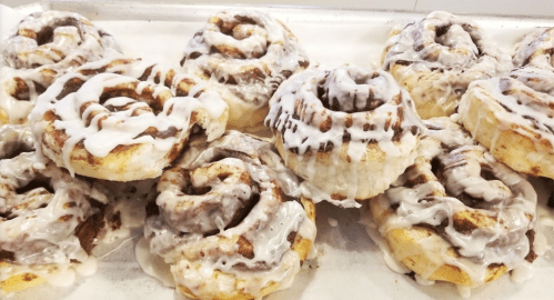 A tray of freshly baked cinnamon rolls drizzled with creamy icing, showcasing their swirled layers and gooey texture.
