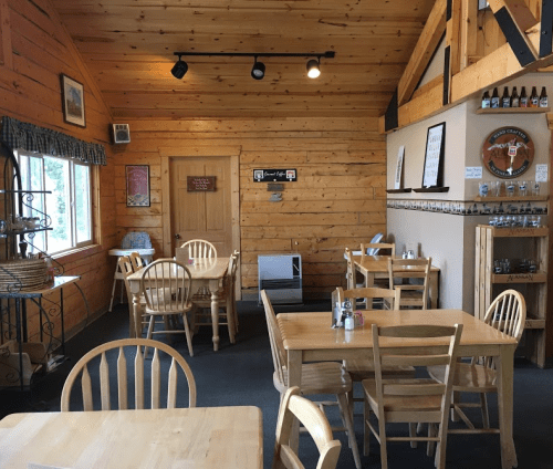 Cozy wooden interior of a restaurant with tables, chairs, and a warm, inviting atmosphere.