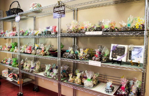 A display of colorful wrapped chocolates and candies on metal shelves, labeled with "sugar-free" options.