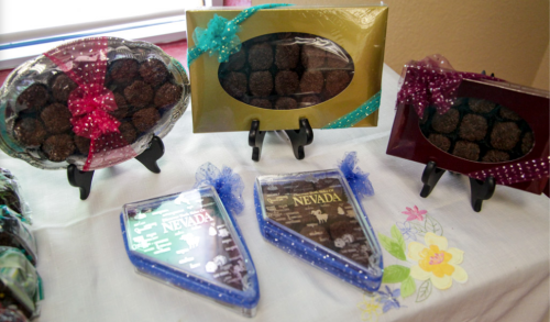 Assorted chocolate treats displayed in decorative packaging on a table, featuring colorful ribbons and stands.