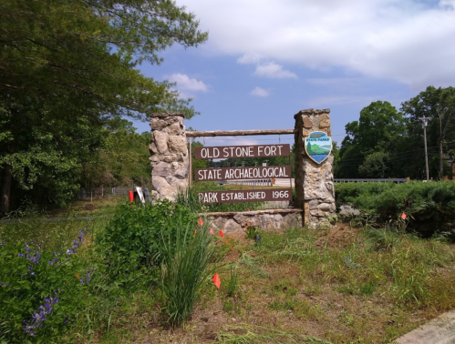 Sign for Old Stone Fort State Archaeological Park, established in 1966, surrounded by greenery and blue sky.