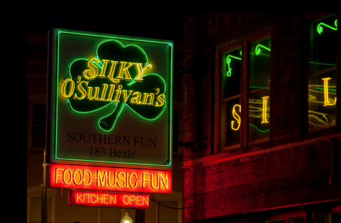 Neon sign for Silky O'Sullivan's featuring a shamrock, advertising food, music, and fun on Beale Street.