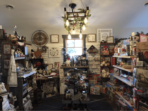 A cozy shop filled with holiday decorations, toys, and gifts, featuring warm lighting and rustic decor.