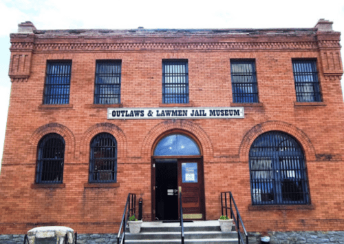 Exterior of the Outlaws & Lawmen Jail Museum, featuring brick walls and barred windows.