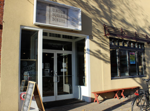 Exterior of Union Square Donuts shop with a welcoming entrance and a bicycle parked outside.