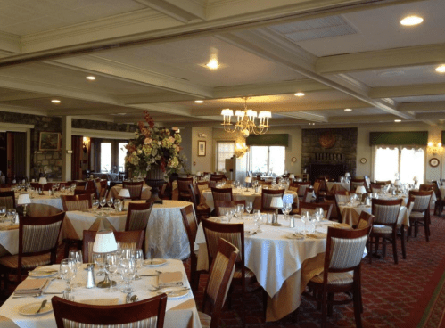 Elegant restaurant interior with neatly set tables, floral centerpiece, and warm lighting. Cozy and inviting atmosphere.