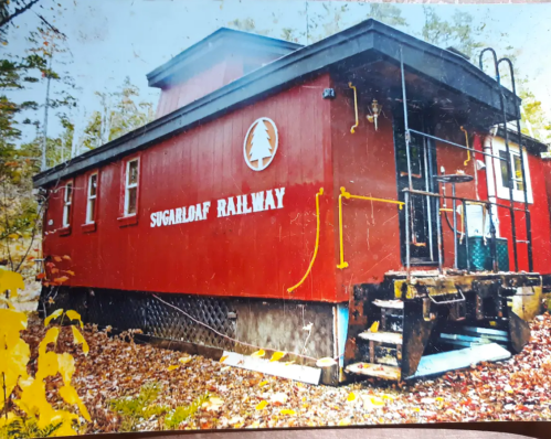 A red building with "Sugarloaf Railway" sign, surrounded by autumn leaves and trees.