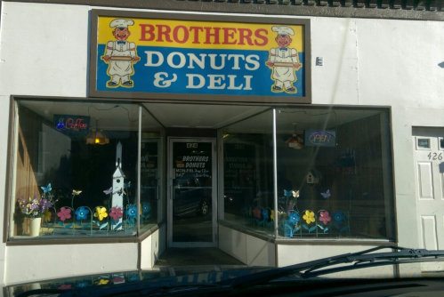 A storefront for "Brothers Donuts & Deli" featuring colorful signage and flower decorations in the windows.