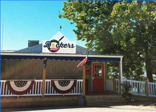 A charming restaurant named "Dockers" with a porch, American flags, and patriotic decorations on a sunny day.