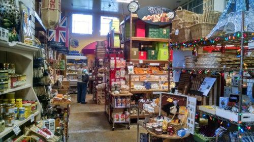 A cozy specialty food store filled with shelves of gourmet products, cheeses, and festive decorations.