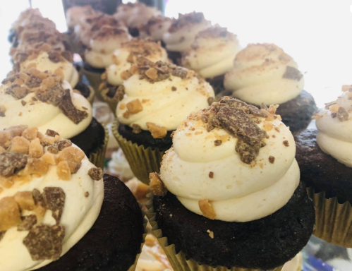 Close-up of chocolate cupcakes topped with creamy frosting and crushed toffee bits.
