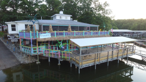 Colorful waterfront café with a thatched roof, surrounded by trees and a dock, marked "CLOSED."
