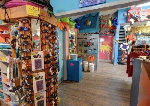 A colorful retail store interior featuring sunglasses, beach gear, and vibrant decor.
