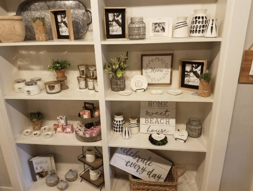 A decorative shelf displaying various home decor items, including frames, vases, and signs with inspirational quotes.