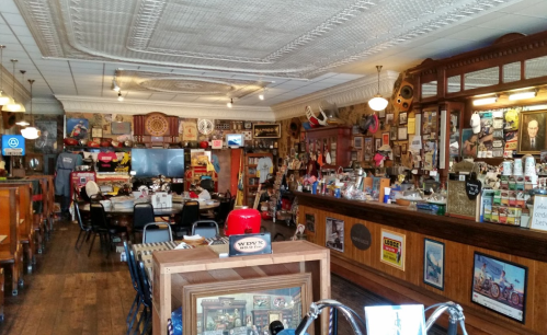 A cozy, vintage-style shop interior filled with memorabilia, a wooden counter, and various decorations on the walls.