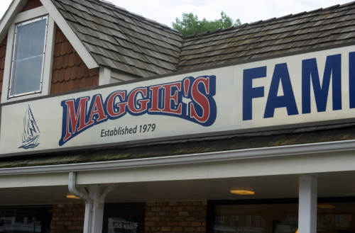 Sign for "Maggie's Family" restaurant, established in 1979, featuring a sailboat graphic and a shingled roof.