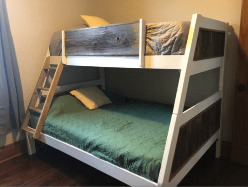 A wooden bunk bed with a top and bottom mattress, featuring a ladder and a rustic design.