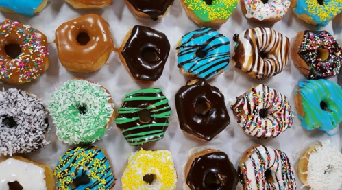 A colorful assortment of donuts with various toppings, including sprinkles, chocolate, and icing, arranged neatly.