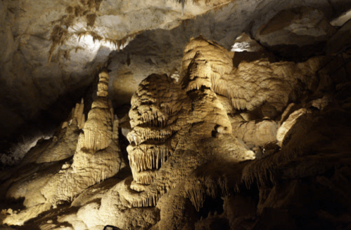 Stalactites and stalagmites in a dimly lit cave, showcasing unique rock formations and textures.