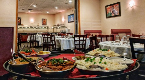 A table set with various Indian dishes, including curries and rice, in a cozy restaurant setting.