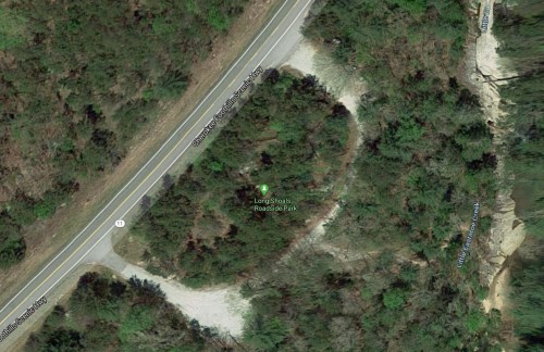 Aerial view of Long Shafts Roadside Park, surrounded by trees, near a winding road.