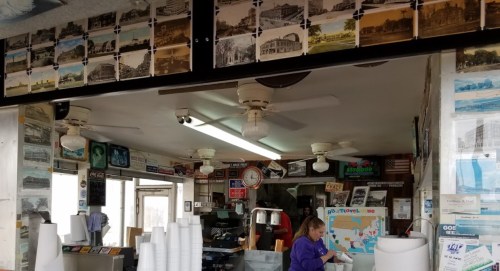 A vintage ice cream shop interior with historical photos, a map, and a staff member serving customers.
