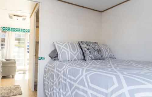 Cozy bedroom with a patterned bedspread, decorative pillows, and a bright window in a modern interior.