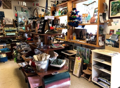A cozy shop filled with various crafts, art, and handmade items displayed on wooden shelves and tables.