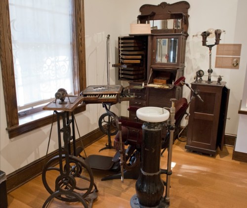 A collection of vintage medical equipment displayed in a museum setting, featuring various tools and furniture.