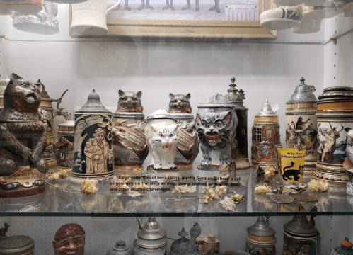 A display of various beer steins and decorative items, featuring animal figures and unique designs.