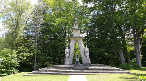 A tall, ornate structure with a tiered design, surrounded by lush greenery and trees.