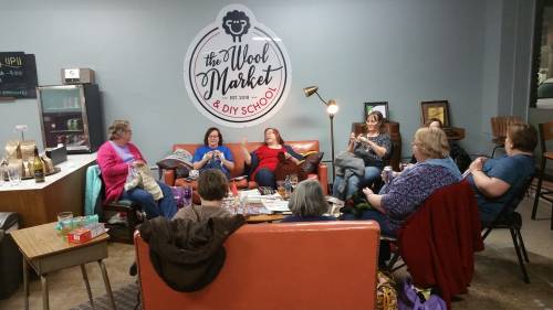 A group of women sitting together in a cozy space, chatting and enjoying each other's company at a DIY school.