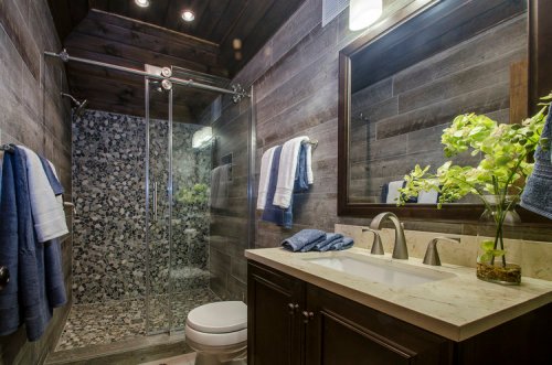 Modern bathroom featuring a glass shower, wooden walls, and a stylish vanity with a vase of flowers.