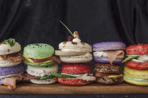 A colorful assortment of macarons filled with various savory ingredients, displayed on a wooden board.