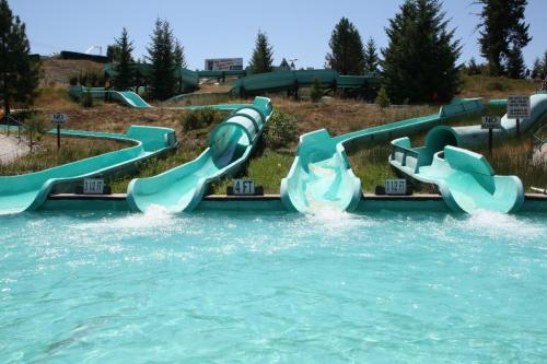 Water slides in a sunny outdoor water park, with turquoise slides and a clear blue pool.