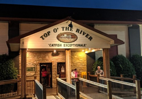Exterior of "Top O' the River" restaurant at night, featuring a sign that reads "Catfish Exceptional" and patrons outside.