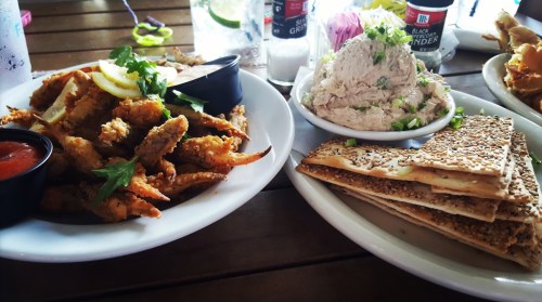A plate of crispy fried seafood with lemon and dipping sauce, alongside a bowl of tuna spread and sesame crackers.