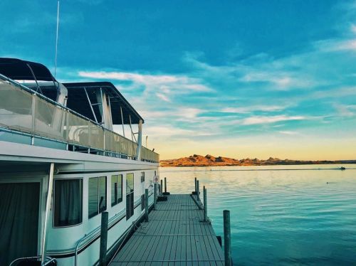 A boat docked at a serene waterfront with calm waters and a clear blue sky in the background.