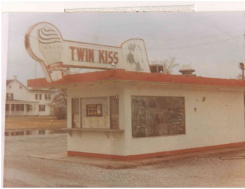 A vintage ice cream stand named "Twin Kiss" with a red and white exterior, set in a rural area.